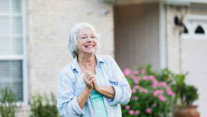 Older woman standing in front of home